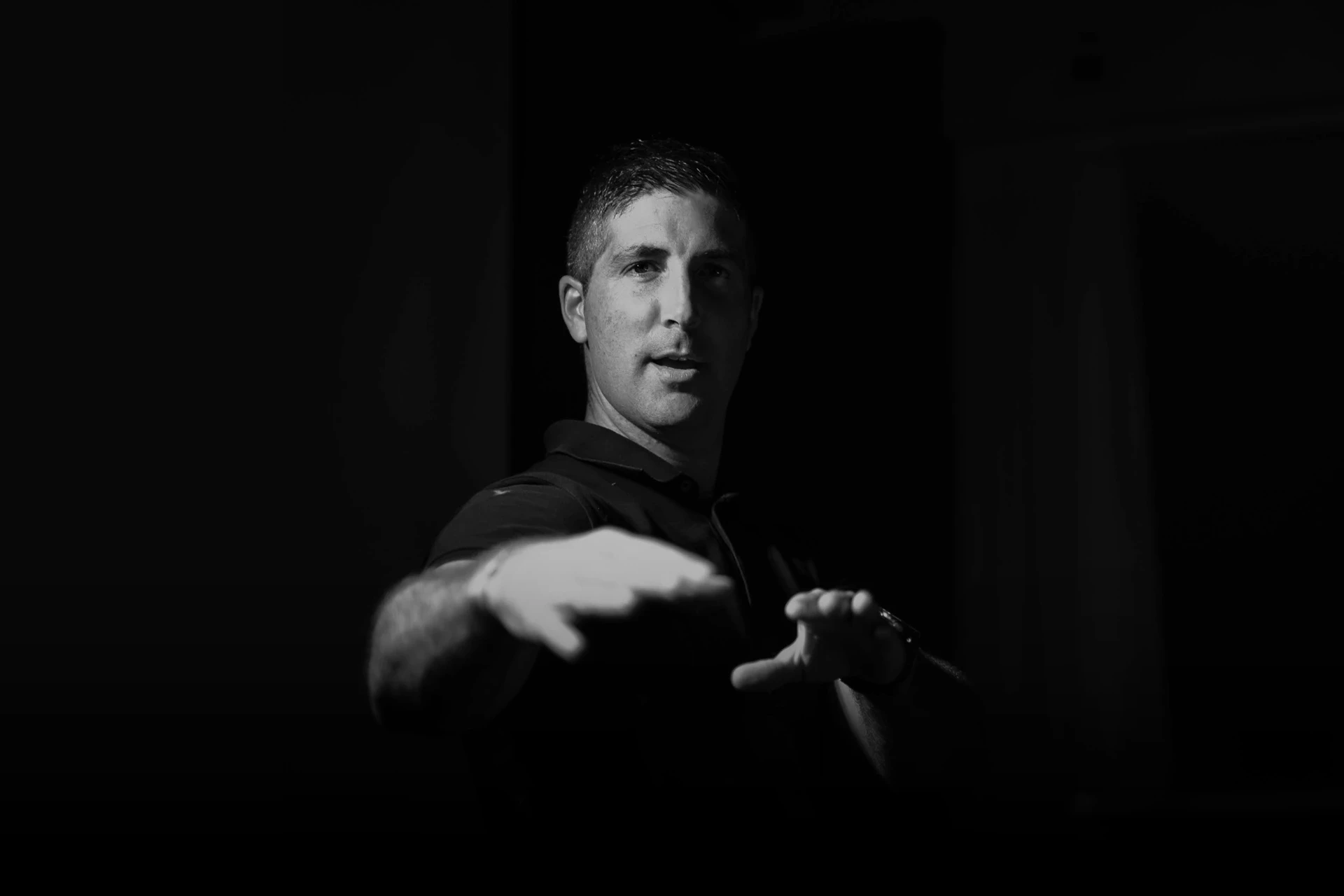 Imagen en blanco y negro de Villa DJ mirando fijamente a la cámara, con los brazos extendidos manteniendo una pose característica de un disc jockey